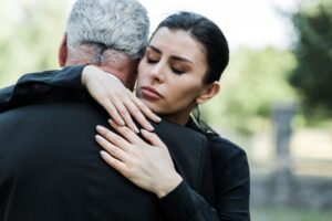 upset woman with closed eyes hugging senior man
